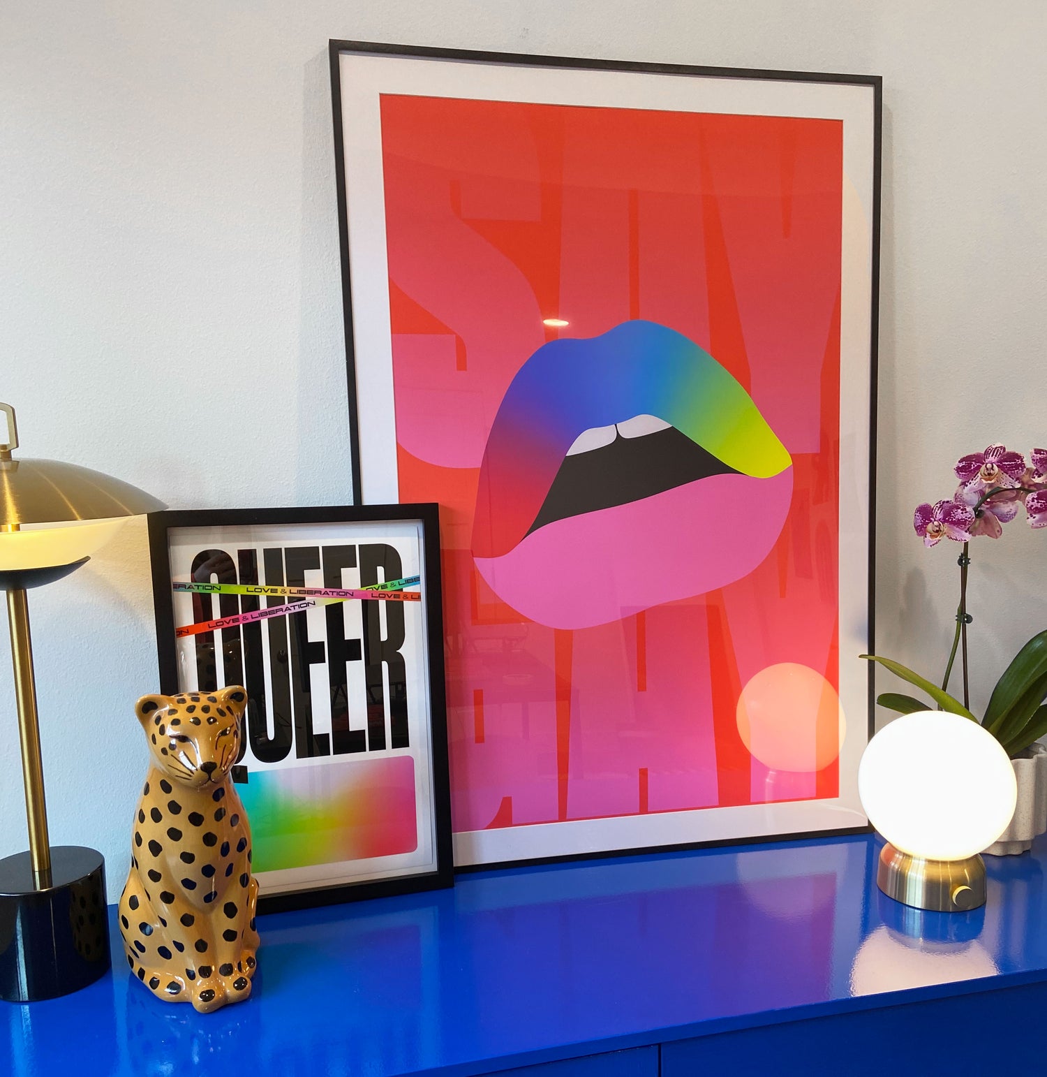 Two Partner posters in frames are displayed on top of a blue dresser with lights and accessories